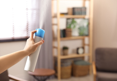 Woman spraying air freshener at home, closeup