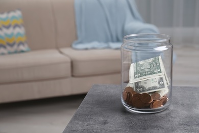 Photo of Donation jar with money on table against blurred background. Space for text