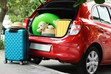 Photo of Suitcases and toys in car trunk outdoors