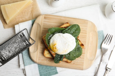 Photo of Delicious poached egg with toasted bread and spinach served on white wooden table, flat lay