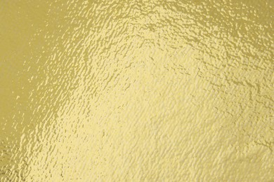 Photo of Edible gold leaf sheet as background, closeup
