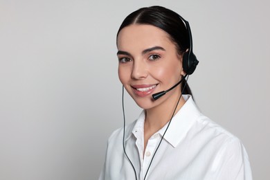 Photo of Hotline operator with modern headset on light grey background, space for text. Customer support