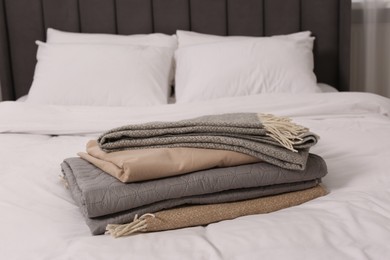 Photo of Stack of different folded blankets on bed in room. Home textile