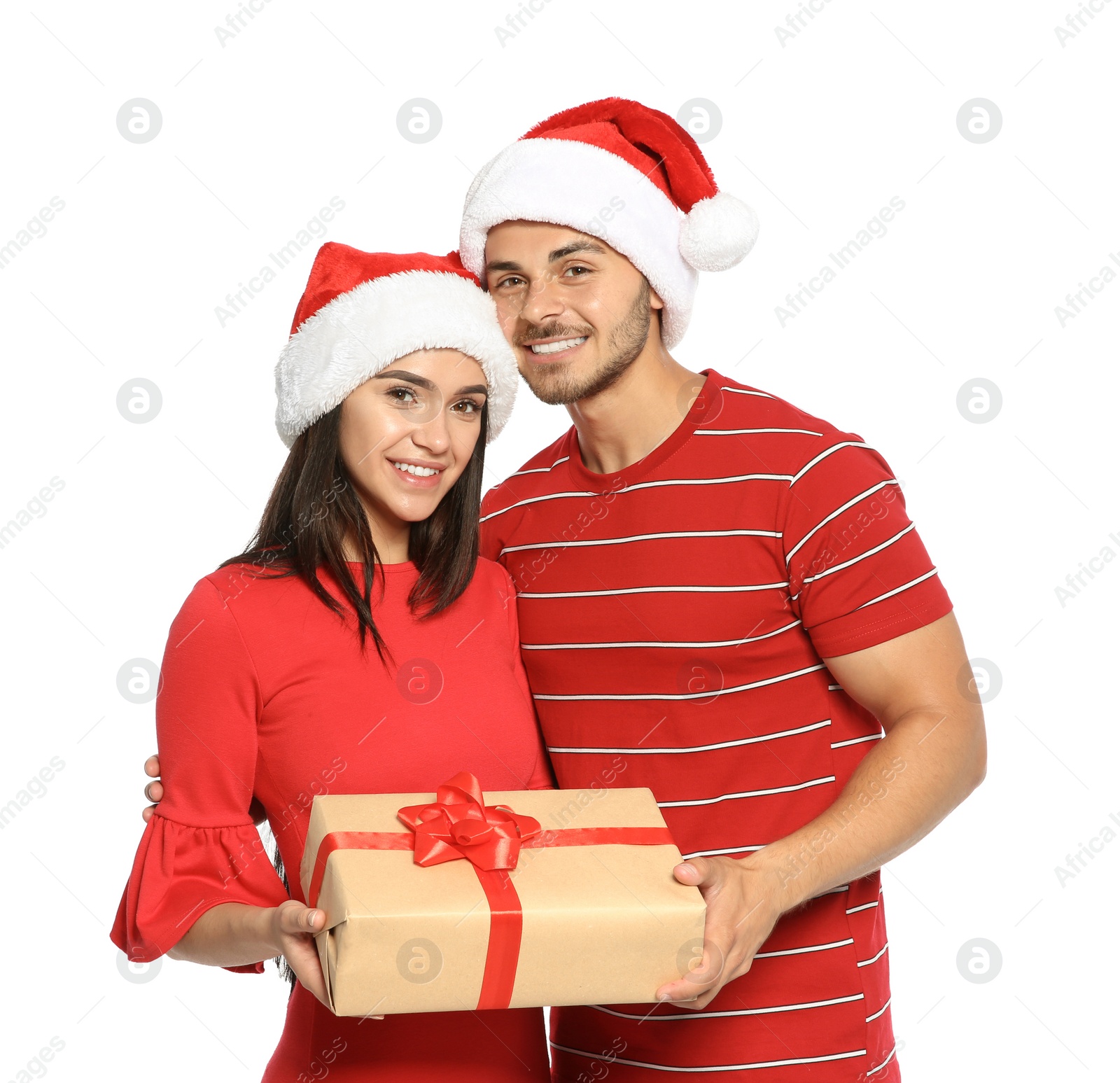 Photo of Young happy couple with Santa hats and gift box on white background. Christmas celebration