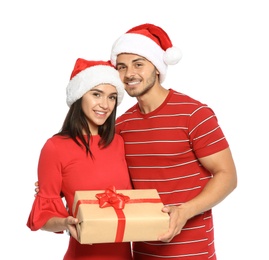 Photo of Young happy couple with Santa hats and gift box on white background. Christmas celebration