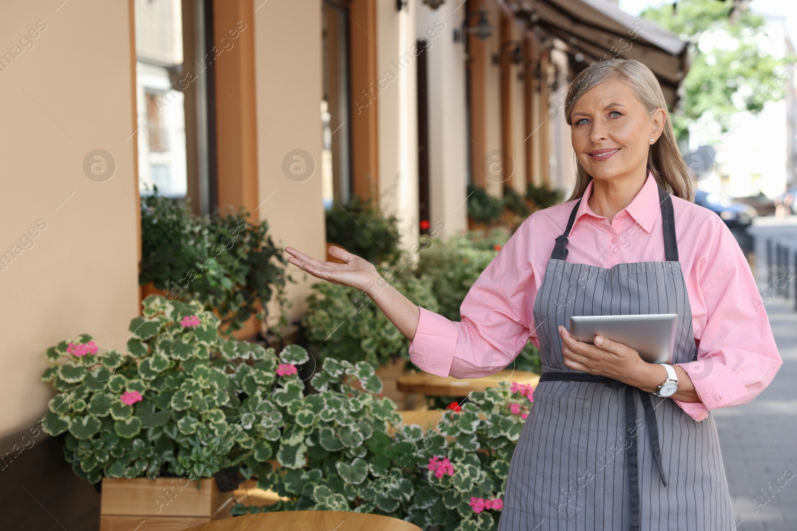 Photo of Happy business owner with tablet inviting to come into her cafe outdoors, space for text