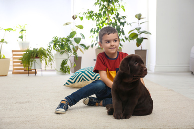 Photo of Little boy with puppy on floor at home. Friendly dog