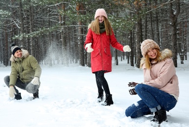 Happy family playing snowballs in winter forest