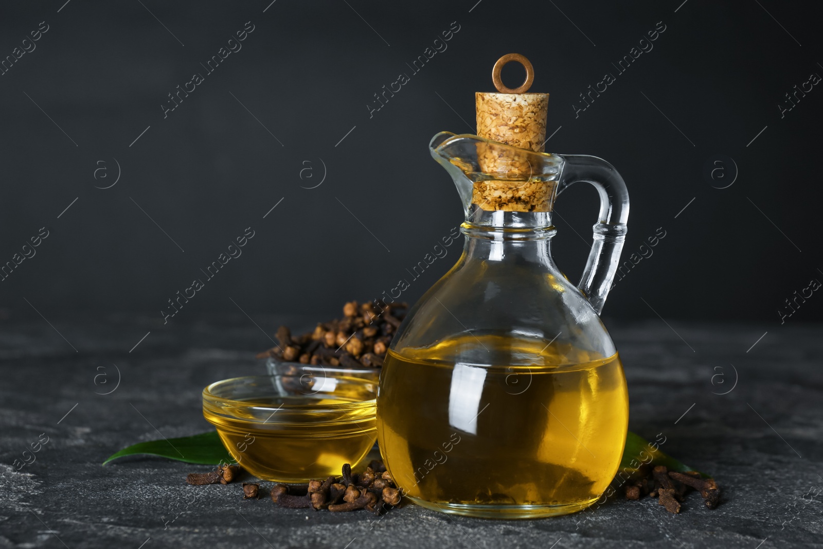 Photo of Essential oil and dried cloves on grey stone table