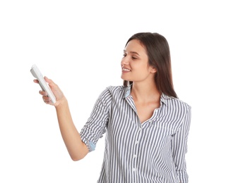 Happy young woman operating air conditioner with remote control on white background