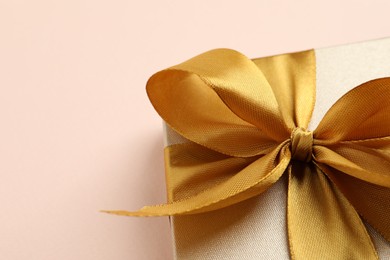 Photo of Beautiful gift box with golden bow on pink background, top view. Space for text