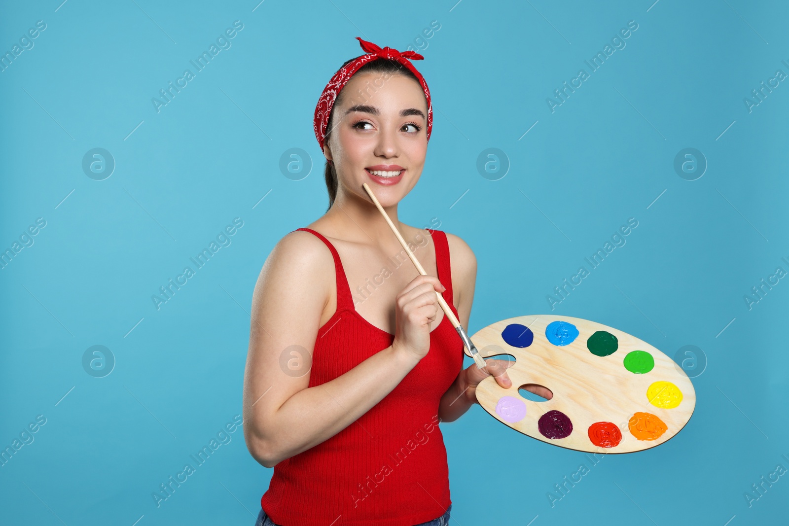 Photo of Woman with painting tools on light blue background. Young artist