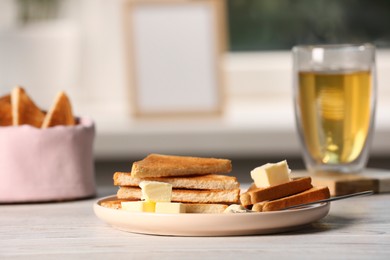 Photo of Tasty toasts with butter served on white wooden table