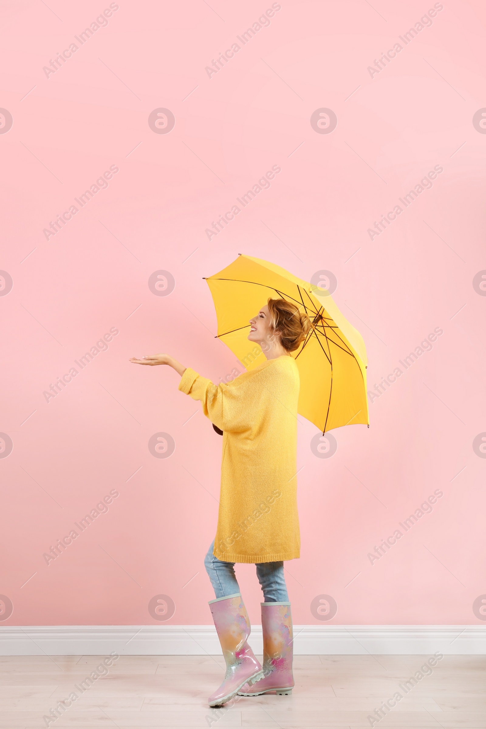 Photo of Woman with yellow umbrella near color wall