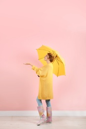 Woman with yellow umbrella near color wall