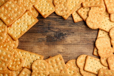 Frame of delicious crackers on wooden table, top view. Space for text