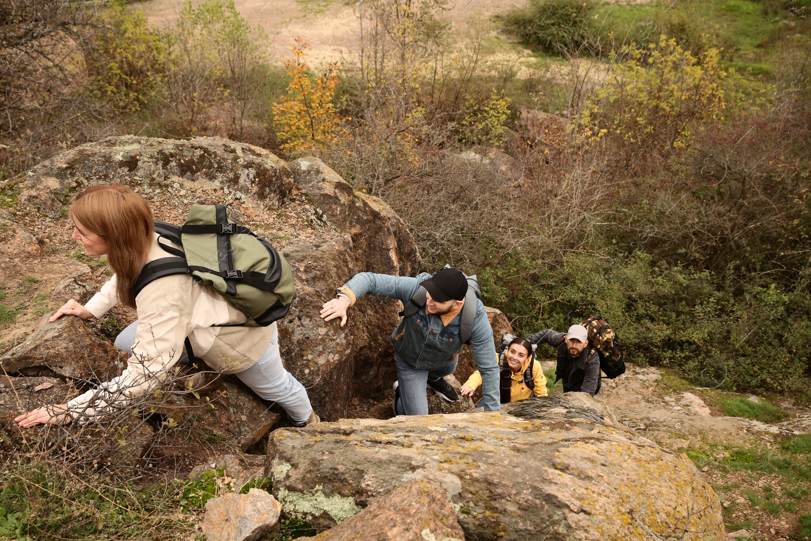 Photo of Group of hikers with backpacks climbing up mountains