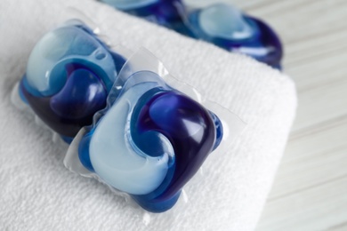 Photo of Laundry capsules and towel on white table, closeup