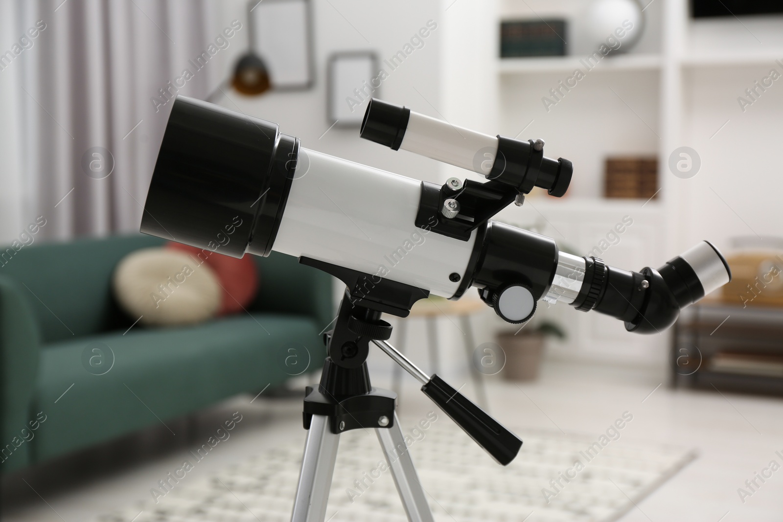 Photo of Tripod with modern telescope in living room