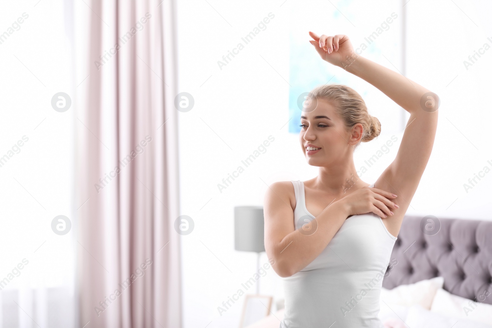 Photo of Beautiful young woman in bedroom. Concept of using deodorant