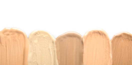 Samples of different foundation shades on white background, top view