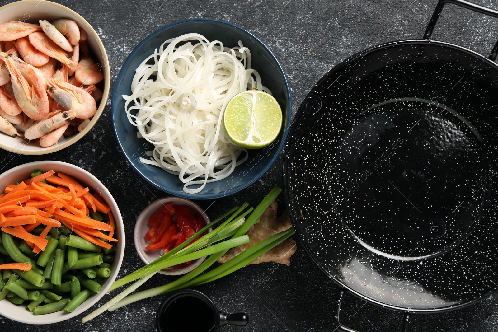 Photo of Flat lay composition with black wok and products on dark textured table