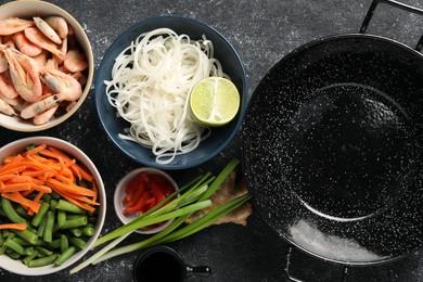 Flat lay composition with black wok and products on dark textured table