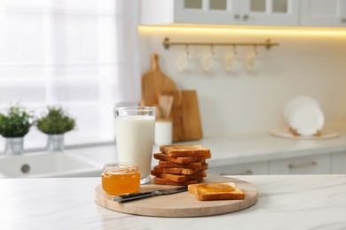 Photo of Breakfast served in kitchen. Crunchy toasts, honey and milk on white marble table