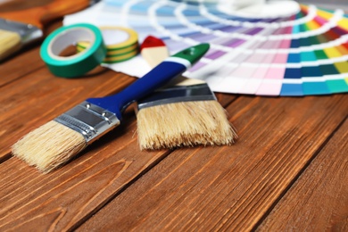 Photo of Brushes and color palette samples on wooden background