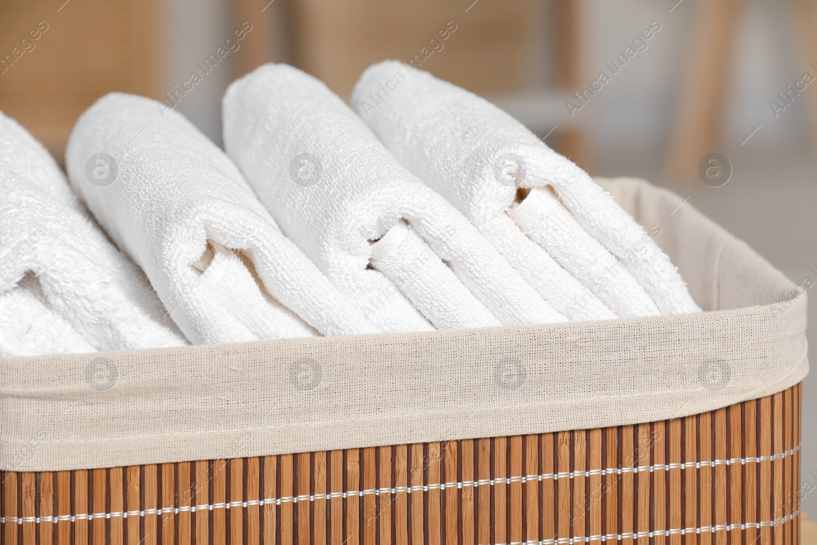 Photo of Wicker basket with folded soft terry towels indoors, closeup