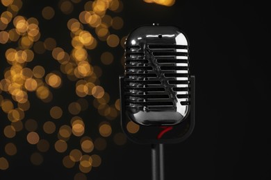 Photo of Vintage microphone against black background with blurred lights, closeup. Sound recording and reinforcement