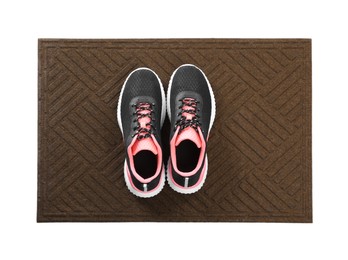 Photo of New clean door mat with shoes on white background, top view