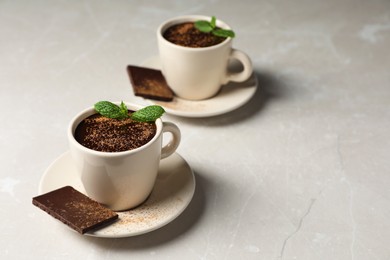 Cup of delicious hot chocolate with fresh mint on grey table. Space for text