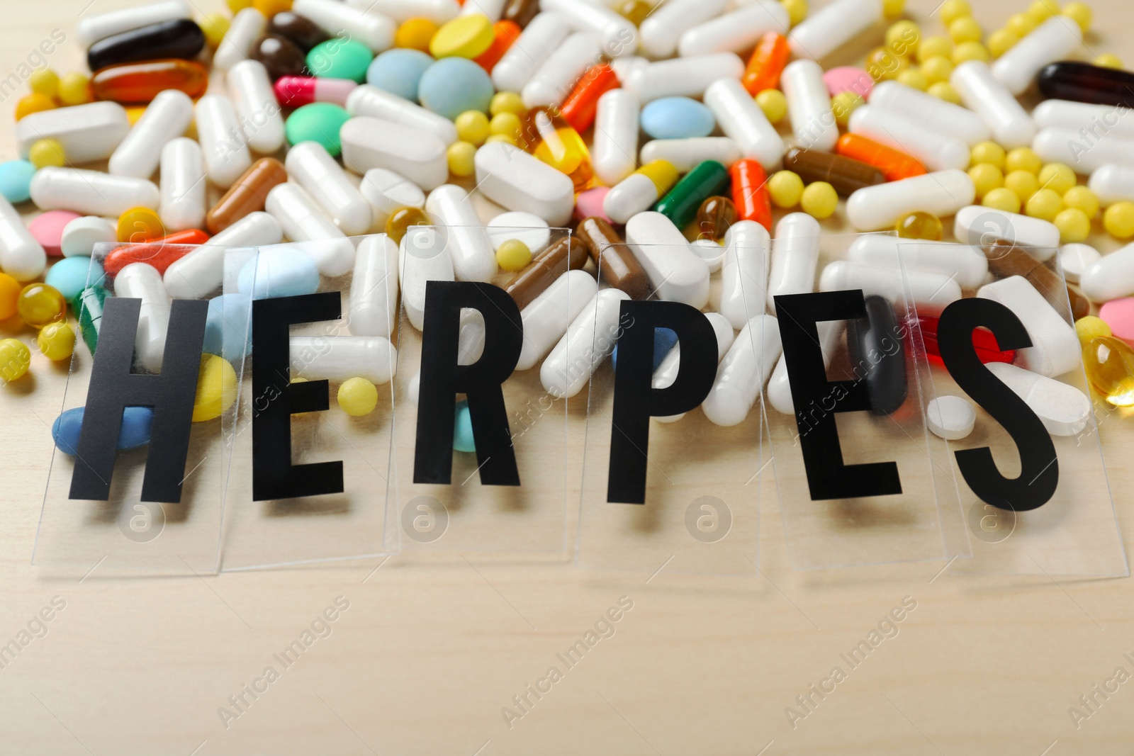 Photo of Word Herpes and different pills on wooden table, above view. Space for text