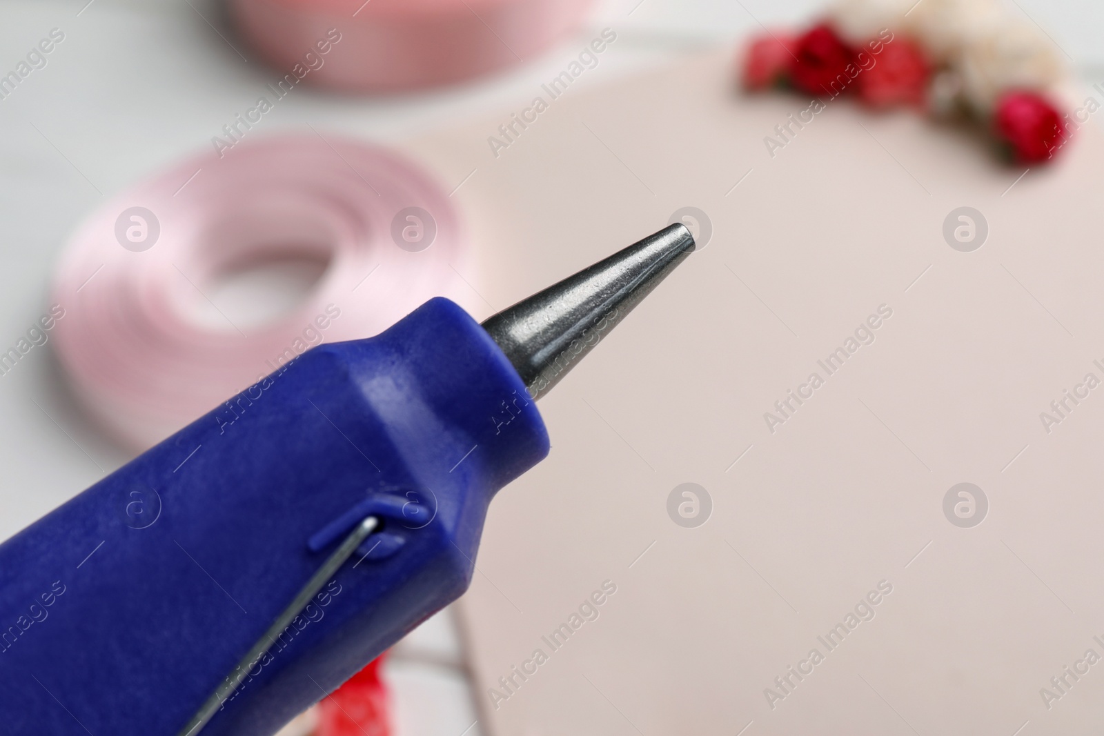 Photo of Hot glue gun on blurred background, closeup