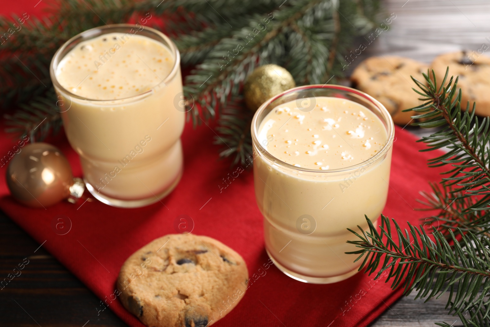 Photo of Tasty eggnog, cookies and fir branches on wooden table