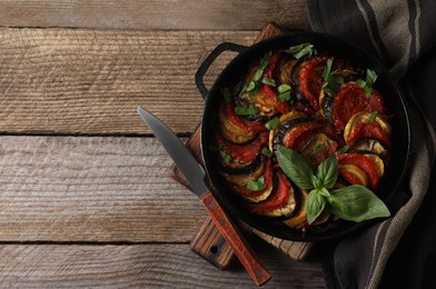 Delicious ratatouille and knife on wooden table, top view. Space for text