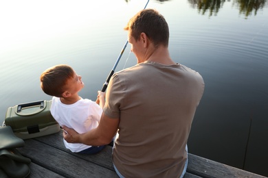 Dad and son fishing together on sunny day