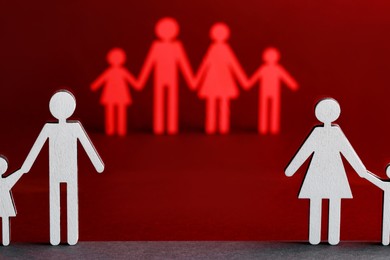 Paper figures of married and divorced family on color background
