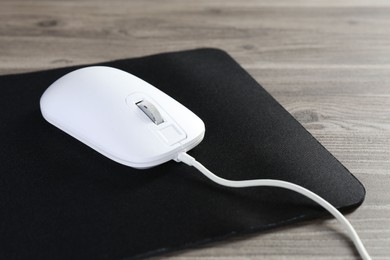 Photo of Wired mouse and mousepad on wooden table