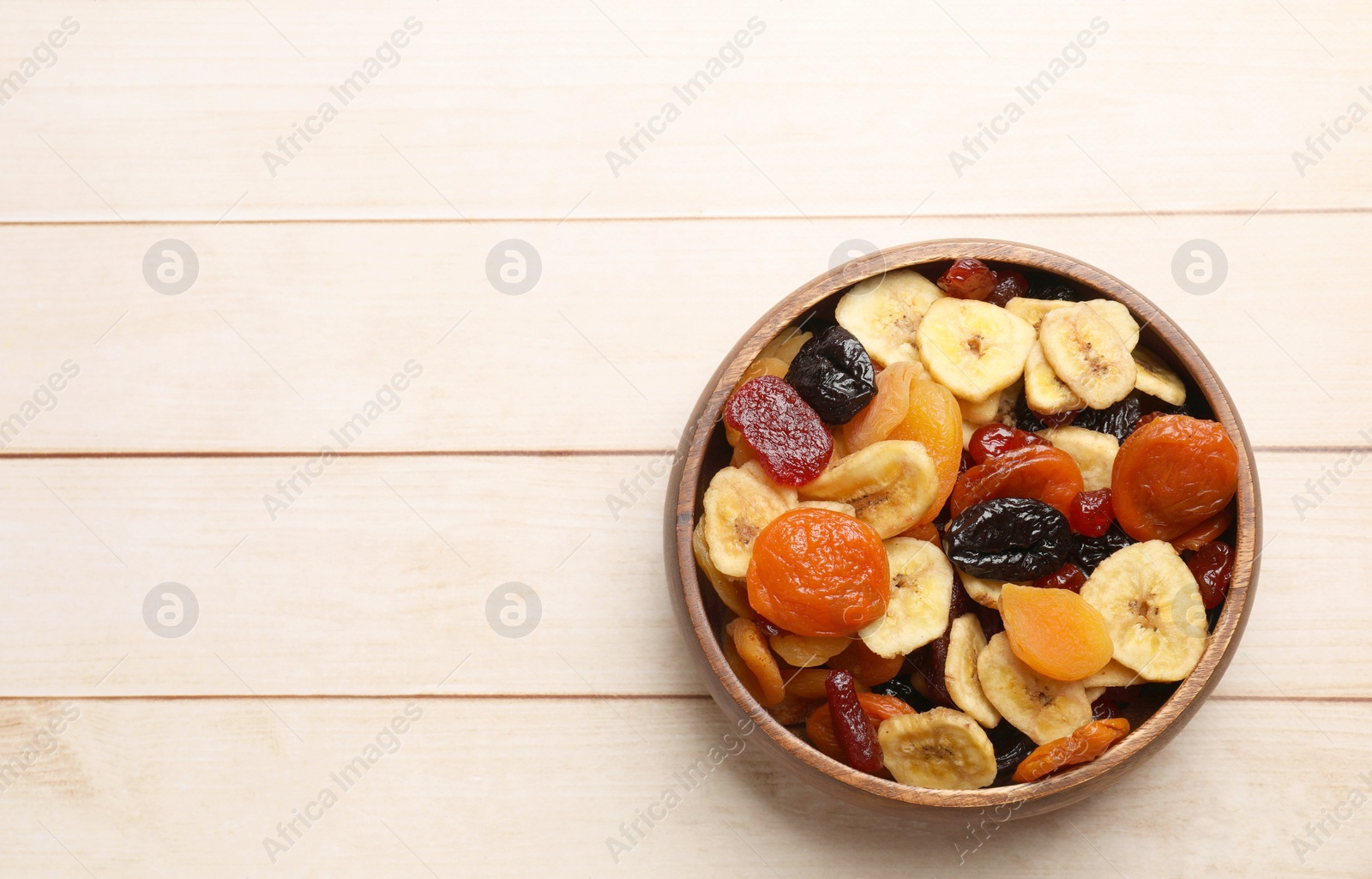 Photo of Mix of delicious dried fruits on white wooden table, top view. Space for text