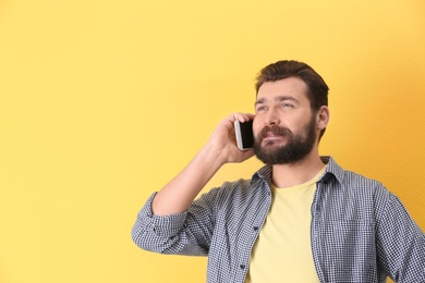 Photo of Portrait of confident mature man with mobile phone on color background