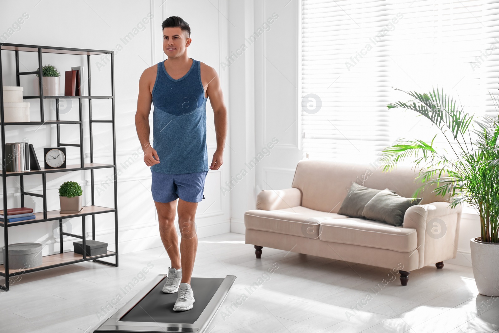 Photo of Sporty man training on walking treadmill at home