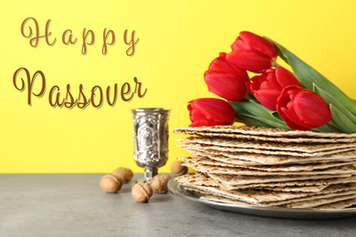 Image of Passover matzos, goblet, walnuts and tulips on grey table. Pesach celebration