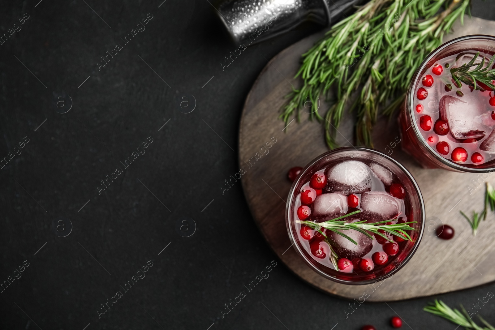 Photo of Tasty refreshing cranberry cocktail with rosemary and fresh ingredients on black table, flat lay. Space for text