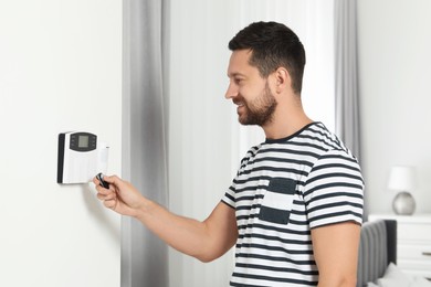 Photo of Home security system. Man using alarm key fob indoors