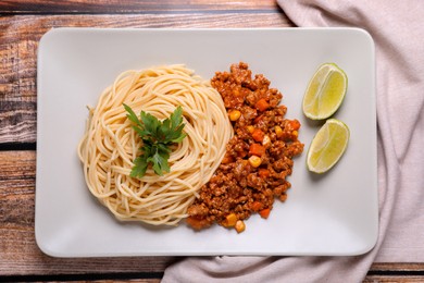Photo of Tasty dish with fried minced meat, spaghetti, carrot and corn served on wooden table, top view