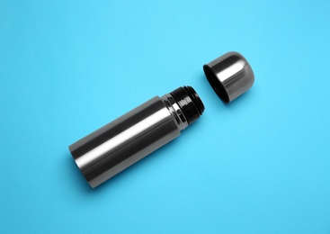 Stainless steel thermos on light blue background, top view