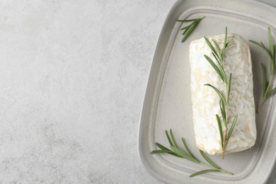 Photo of Delicious fresh goat cheese with rosemary on light grey table, top view. Space for text