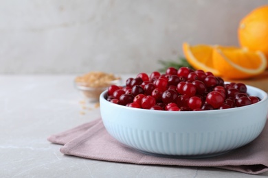 Photo of Fresh ripe cranberries in bowl on light table. Space for text
